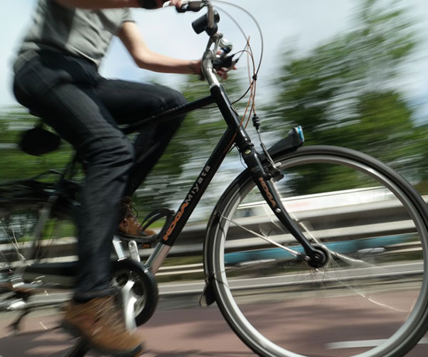 Bilden visar en människa som cyklar, bakgrunden är ur fokus