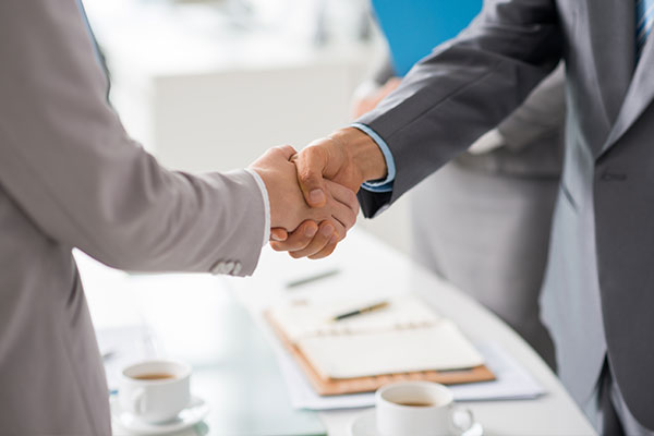 Bilden visar ett handslag mellan två affärsmänniskor