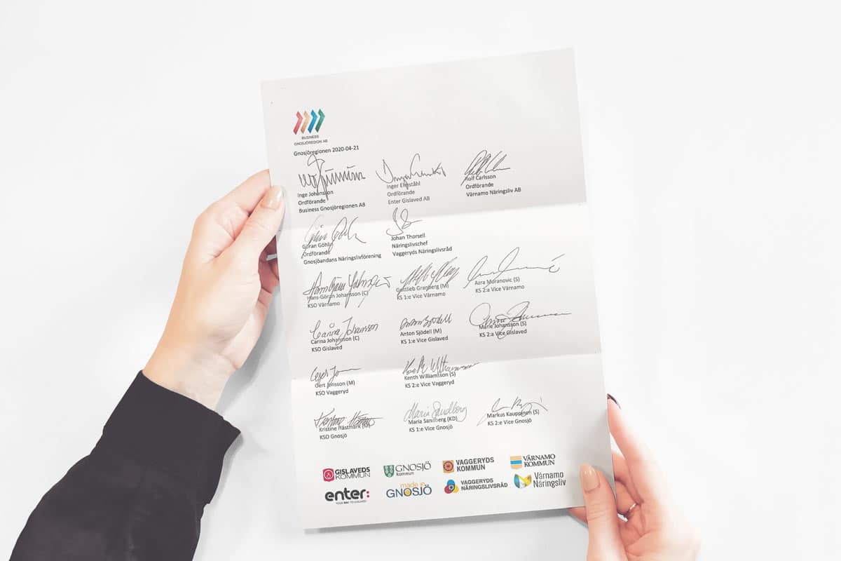 Bilden visar två händer som håller i ett A4 dokument med signaturer