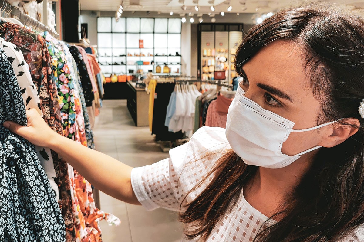 Bilden visar en ung dam som handlar kläder i en butik under coronapandemin